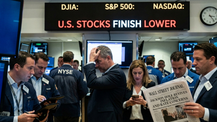 Traders on the New York Stock Exchange floor react beneath an electronic board reading “U.S. Stocks Finish Lower,” while a newspaper headline references Jackson Hole, inflation concerns, and interest rates.