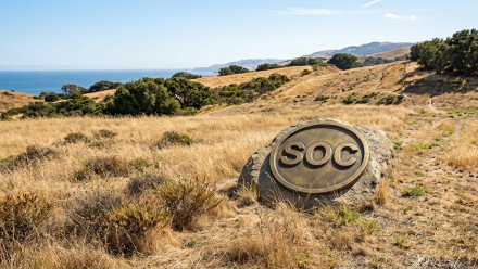 Coastal California hills overlooking the Pacific Ocean, with a large engraved stone displaying “SOC,” representing Sable Offshore Corp. (NYSE: SOC) and its Santa Ynez Pipeline System operations.