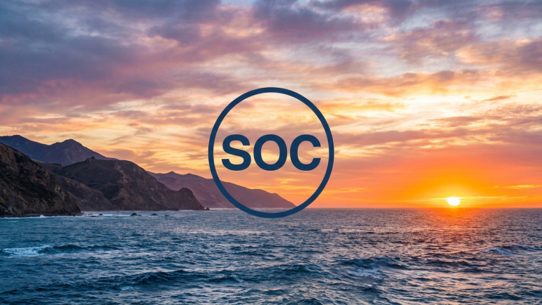 Sunset over California’s Pacific coastline with ocean waves and rugged cliffs, featuring a circular navy “SOC” graphic representing Sable Offshore Corp. (NYSE: SOC).